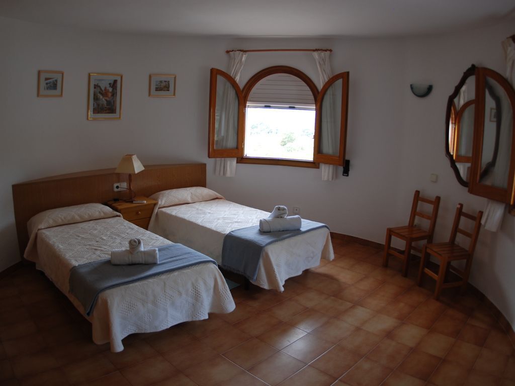 Une chambre avec deux lits, une fenêtre avec des rideaux, une chaise et un miroir.