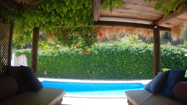 A poolside area with two lounge chairs, a wooden deck, and a view of a swimming pool.
