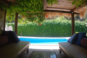 A poolside area with two lounge chairs, a wooden deck, and a view of a swimming pool. - Amazing Air-Con Villa with pool, Wifi, Close to Santa Eulalia and Ibiza Town (IB)
