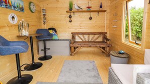 En stuga med träpanel på insidan, innehållande en matplats, en bänk, ett fönster med utsikt och diverse väggdekorationer.