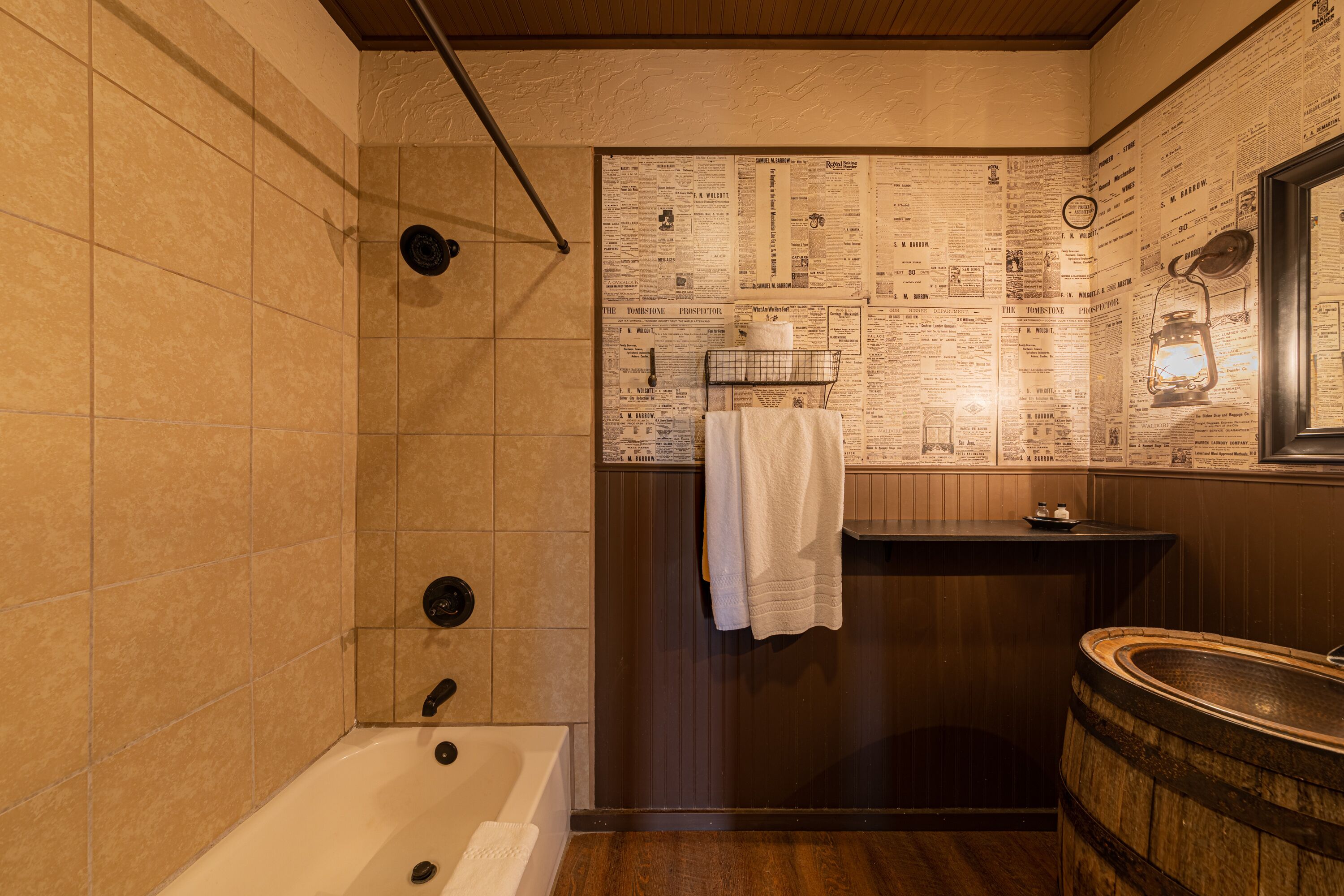 A bathroom with a bathtub, wooden vanity, and newspaper-covered walls.