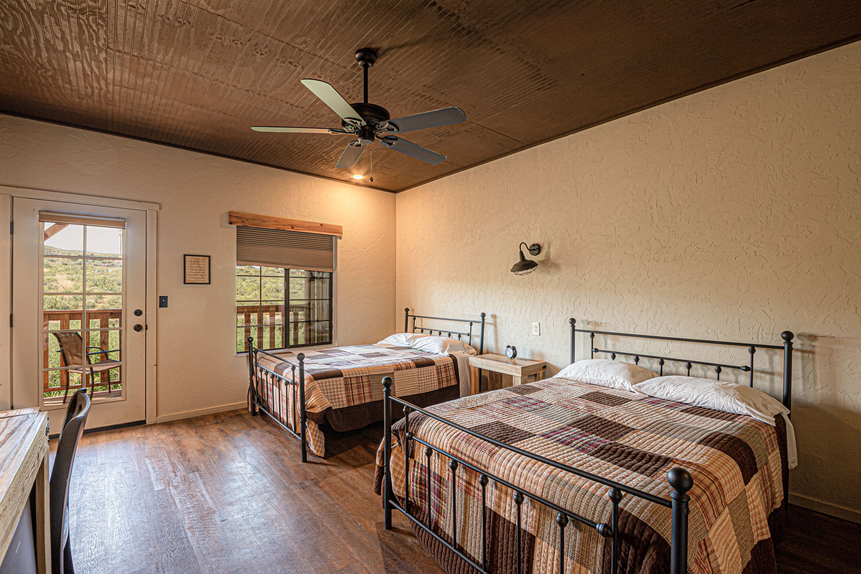 A bedroom with two beds, a ceiling fan, and a window with a view.