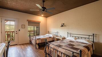 A bedroom with two beds, a ceiling fan, and a window with a view.