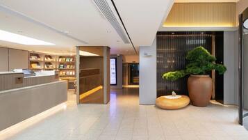 A modern reception area with a counter, bookshelves, and a digital display.
