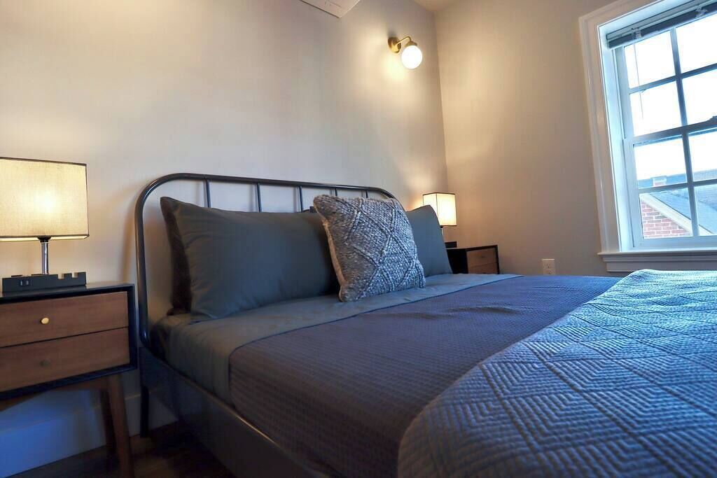 Une chambre à coucher avec un lit, deux tables de chevet, une lampe et une fenêtre.