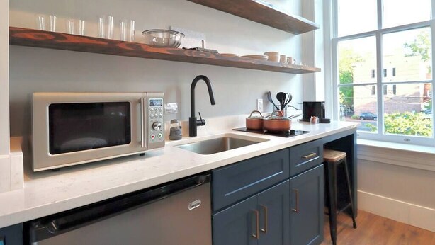 Una cocina con microondas, fregadero y estantes de madera.