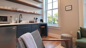 Una cocina moderna con microondas integrado, cafetera y estantes de madera.