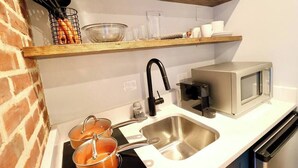 Een keuken met een roestvrijstalen spoelbak, een magnetron en een houten plank boven het aanrecht.