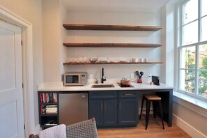 Una cocina compacta con electrodomésticos integrados, una ventana y una estantería.