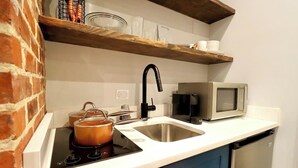 A compact kitchen with a built-in stove, a sink, a microwave, and a dishwasher. - The Prince Suite at Prince Street Inn (Alexandria)