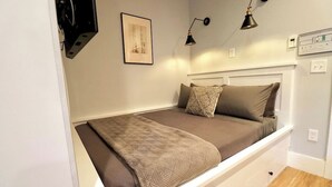 A single bed with a headboard, a bedside table, a wall-mounted lamp, and a framed picture on the wall. - The Prince Suite at Prince Street Inn (Alexandria)