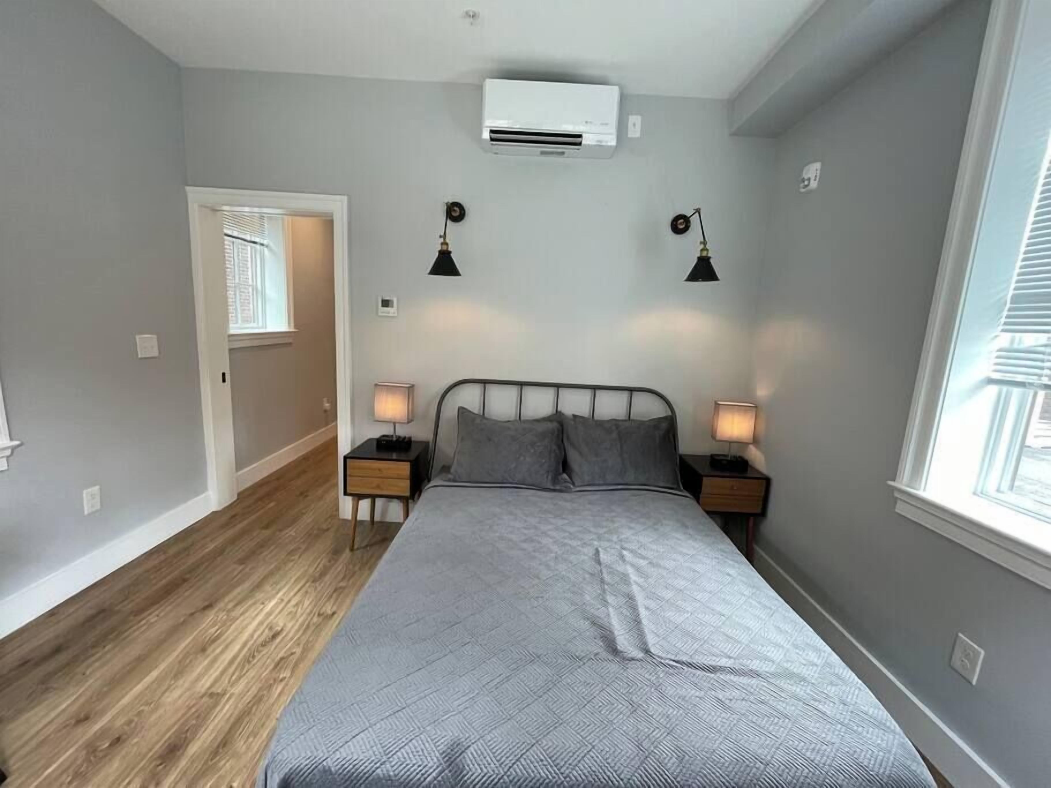 Una camera da letto con un letto, lampade da comodino, un condizionatore d'aria e una finestra.