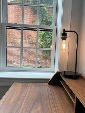 Una habitación con ventana, un escritorio y una lámpara de mesa.