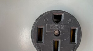 A round electrical outlet with two switches and a central screw. - Texas Grand Slam (City-by-the Sea)