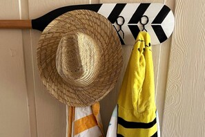 A straw hat, yellow towel, and a black and white paddle on a wall. - Texas Grand Slam (City-by-the Sea)