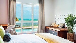 A hotel room with a large window, a bed, a desk, and a view of the ocean. - Villa Tropic Lagoon,  by the lagoon! (Le François)
