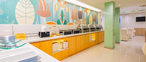 A modern breakfast bar with a colorful mural, buffet setup, and a clean, well-lit room.