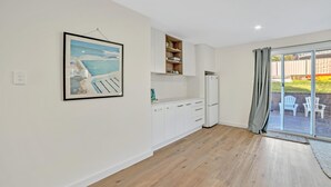 Eine moderne Küche mit weißen Schränken, einem integrierten Kühlschrank und einem großen Fenster mit Blick ins Freie.