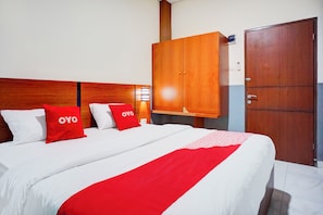 A hotel room with a large bed, two red pillows, a wooden wardrobe, and a door. - Hotel O Sean's Residence Mansyur Near USU (Medan)