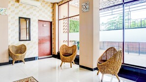 A modern interior with a patterned wall, a large window, and three wicker chairs. - Hotel O Sean's Residence Mansyur Near USU (Medan)