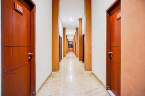A hotel hallway with wooden doors, numbered signs, and a marble floor. - Hotel O Sean's Residence Mansyur Near USU (Medan)