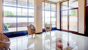 A spacious lobby with large windows, two wicker chairs, and a polished floor. - Hotel O Sean's Residence Mansyur Near USU (Medan)