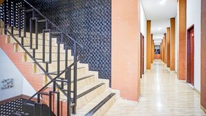 A hotel corridor with a staircase, a patterned wall, and a long hallway with doors. - Hotel O Sean's Residence Mansyur Near USU (Medan)