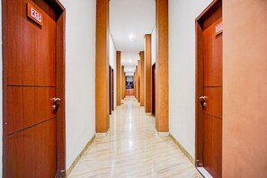 A hotel hallway with wooden doors, numbered signs, and a marble floor.