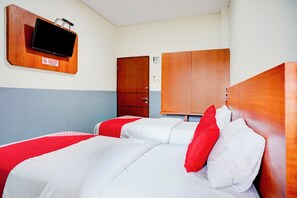 A hotel room with two beds, a television mounted on a wooden panel, a wardrobe, and a door with a sign.