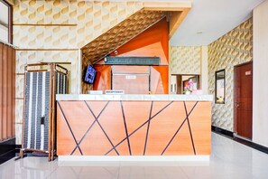 A reception desk with a 'RECEPTIONIST' sign, a television, and a wooden counter with a geometric pattern.