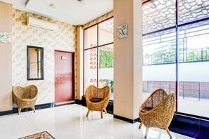 A modern interior with a patterned wall, a large window, and three wicker chairs. - Hotel O Sean's Residence Mansyur Near USU (Medan)