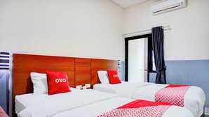 A hotel room with two beds, each with white bedding and red accents, a wooden headboard, and a window with a curtain. - Hotel O Sean's Residence Mansyur Near USU (Medan)