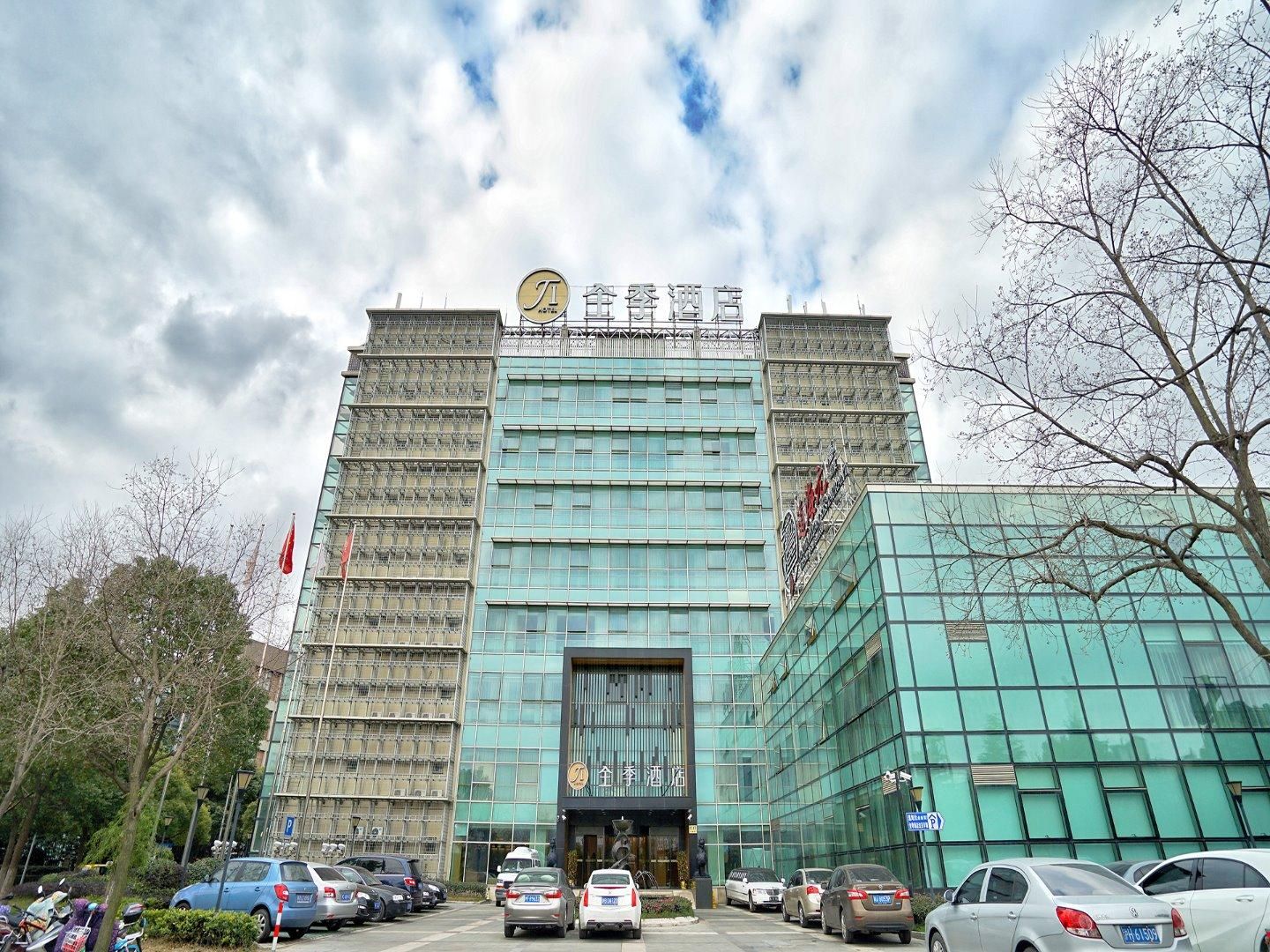 A hotel with a modern glass facade, a prominent entrance, and a parking lot in front.