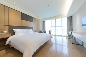 Una habitación de hotel moderna con una cama grande, un escritorio y un televisor.