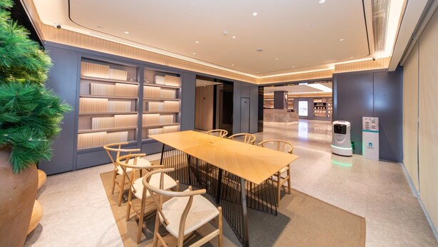 A modern conference room with a long table, chairs, and bookshelves. - Ji Hotel (Xi'an)