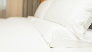 A bed with white bedding and a wooden headboard. - Ji Hotel (Xi'an)