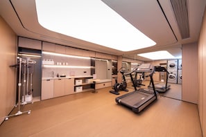 A modern, well-lit room with a large mirror, a treadmill, and a compact exercise area. - Ji Hotel (Xi'an)
