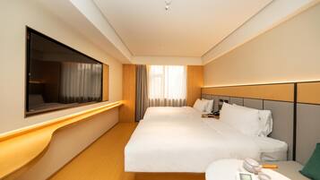 A hotel room with a large bed, bedside tables, a TV, and a window with curtains.