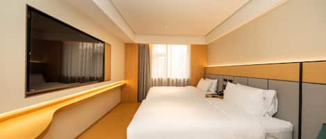 A hotel room with a large bed, bedside tables, a TV, and a window with curtains.