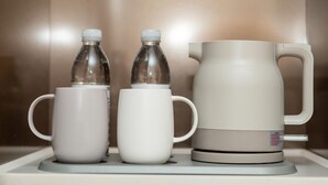 A coffee maker with two mugs and two bottles on a countertop. - Ji Hotel (Xi'an)