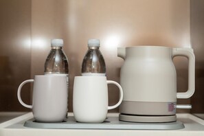A coffee maker with two mugs and two bottles on a countertop. - Ji Hotel (Xi'an)