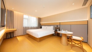 A modern hotel room with a large bed, bedside table, and a small round table with chairs. - Ji Hotel (Xi'an)