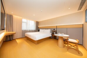 A modern hotel room with a large bed, bedside table, and a small round table with chairs. - Ji Hotel (Xi'an)