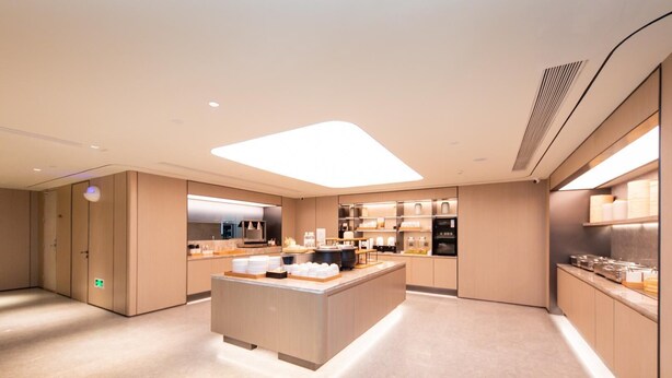 A modern hotel kitchen with a central island, built-in appliances, and a clean, minimalist design.