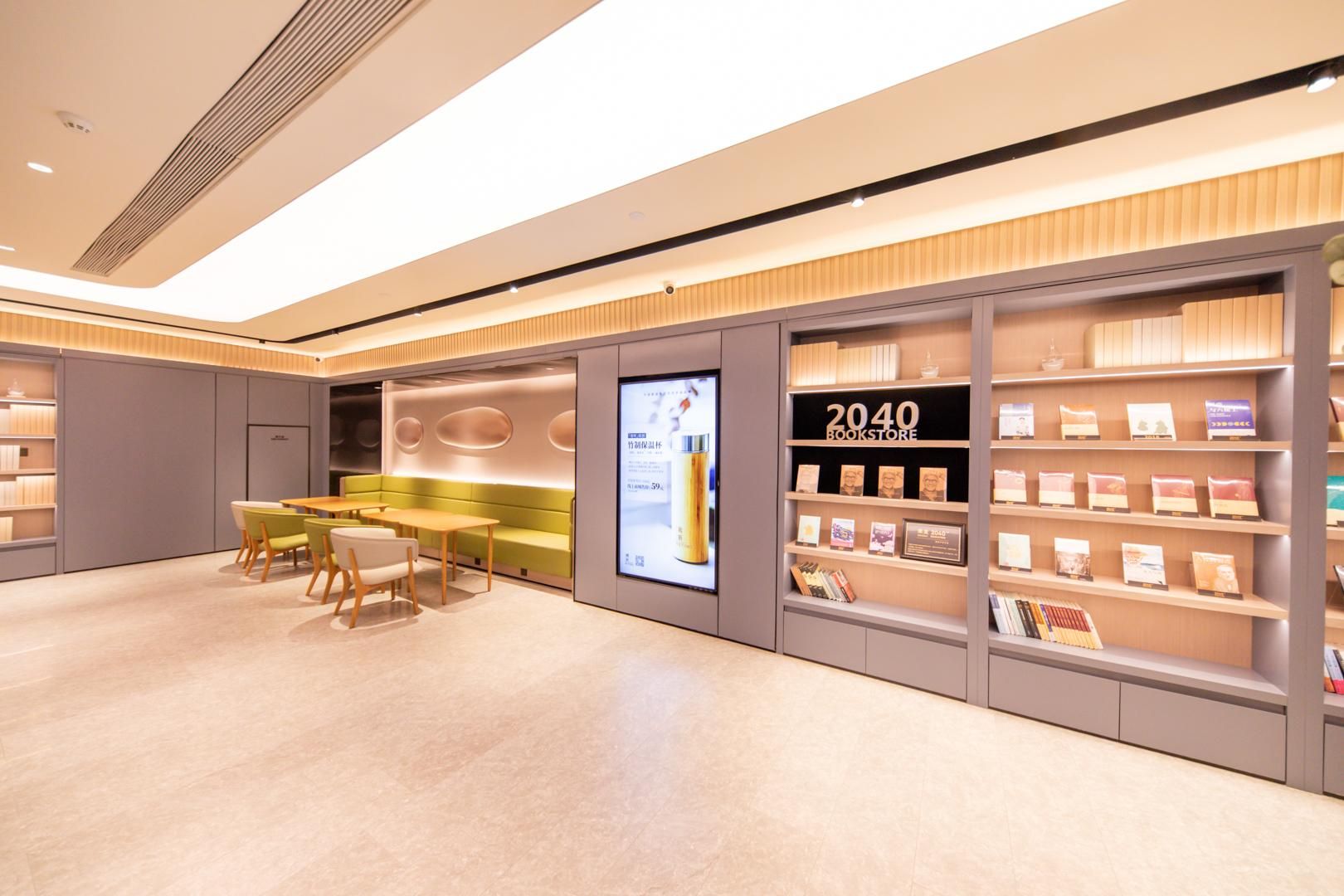 A modern bookstore interior with a seating area, bookshelves, and a digital display.