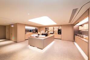 A modern hotel kitchen with a central island, built-in appliances, and a clean, minimalist design. - Ji Hotel (Xi'an)