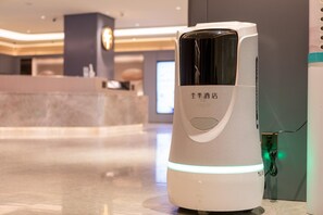 A modern hotel reception area with a white, illuminated reception desk and a digital display. - Ji Hotel (Xi'an)
