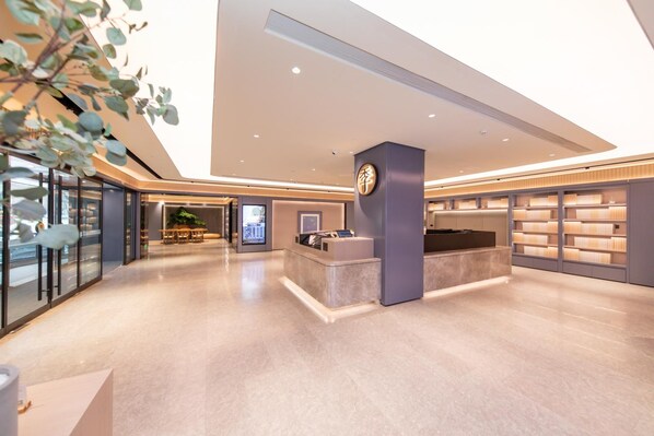 A modern hotel lobby with a reception desk, a digital information kiosk, and a bookshelf. - Ji Hotel (Xi'an)