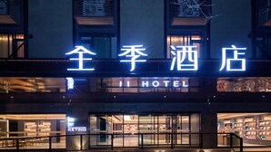 A hotel entrance with a neon sign in a foreign language, a visible "HOTEL" sign, and a bookstore on the right side.