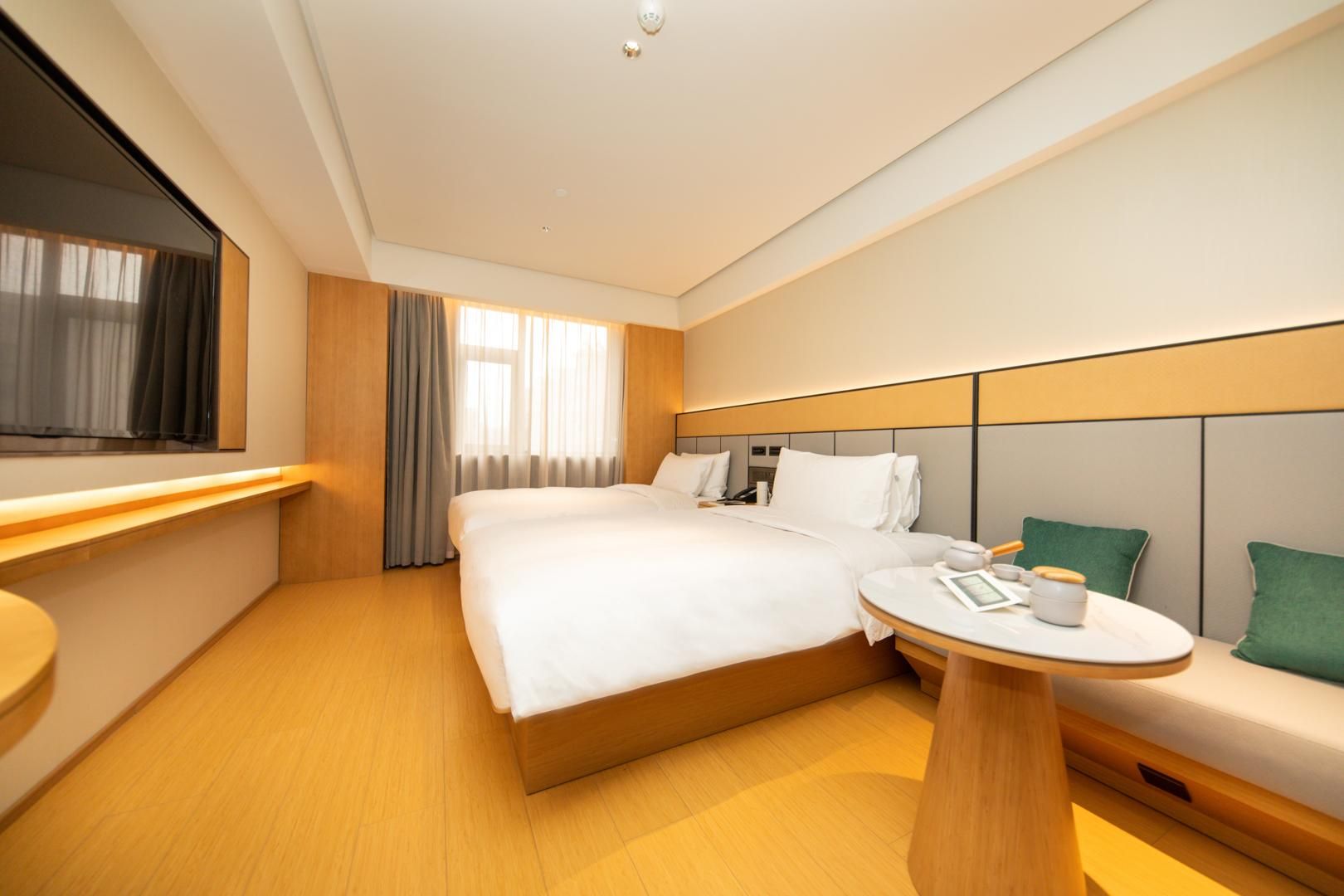 A hotel room with a large bed, bedside table, and a small round table with a cup and saucer.